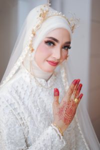 Muslim Bride in white showing hand with Henna and a ring